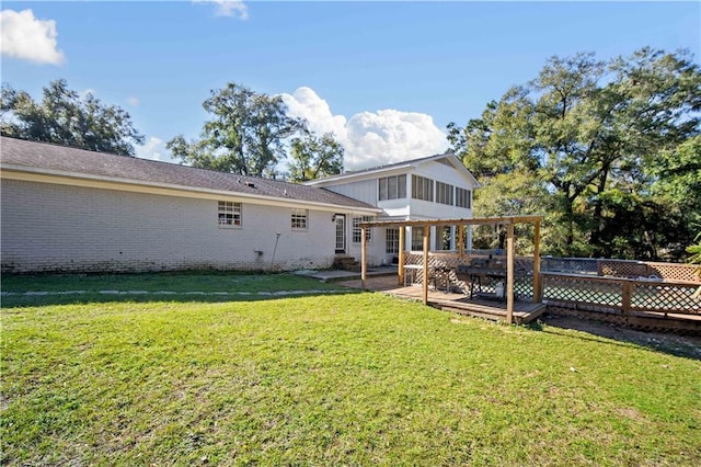 rear view of house featuring a yard, a sunroom, and a wooden deck