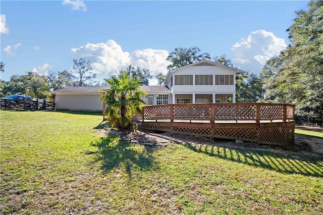 rear view of house featuring a sunroom, a yard, and a wooden deck