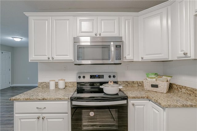 kitchen featuring white cabinetry, tasteful backsplash, stainless steel appliances, wood-type flooring, and light stone countertops