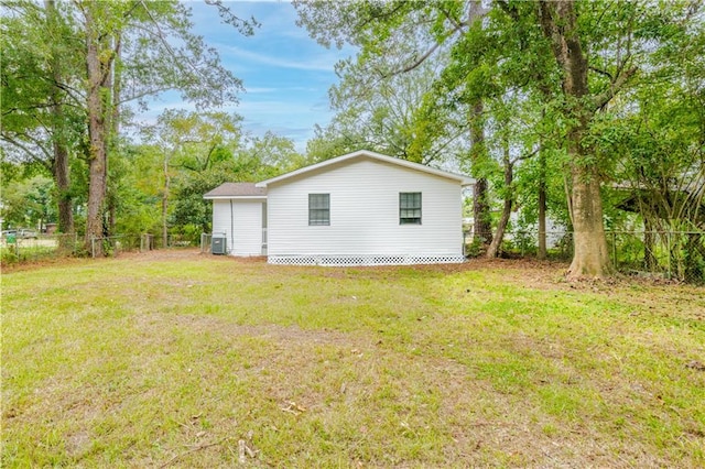 view of side of property with central AC and a yard