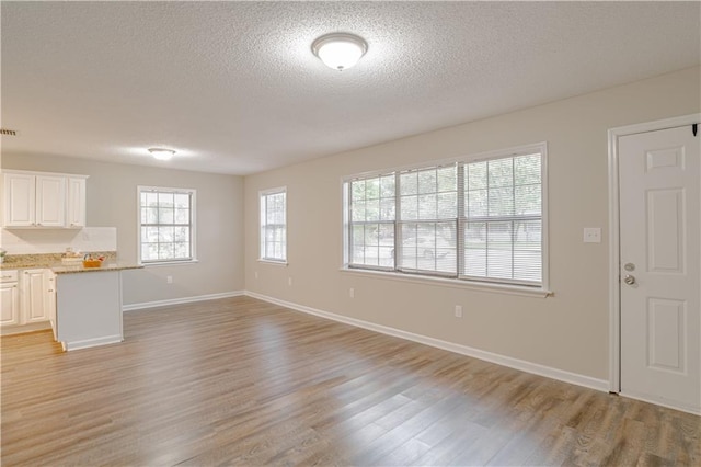 unfurnished living room featuring a textured ceiling and light wood-type flooring