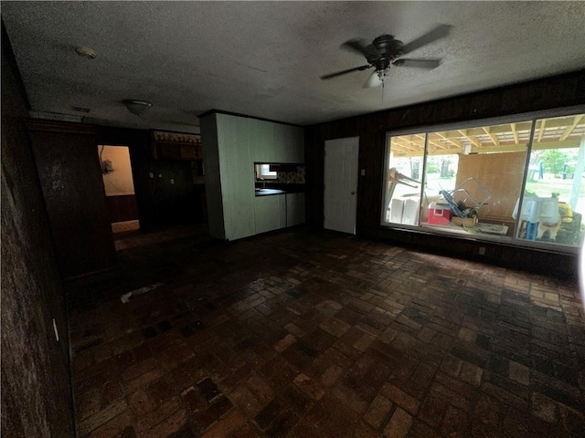 unfurnished living room with a textured ceiling and ceiling fan