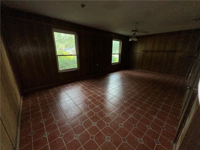 spare room with ceiling fan and wood walls