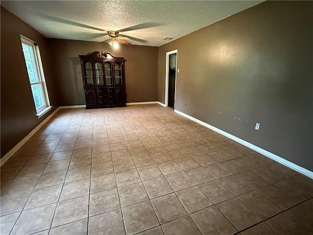 tiled spare room with ceiling fan and a textured ceiling