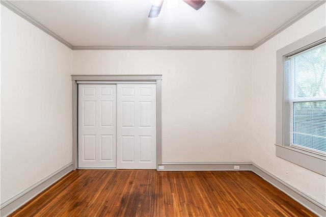 unfurnished bedroom featuring ceiling fan, dark hardwood / wood-style flooring, crown molding, and a closet