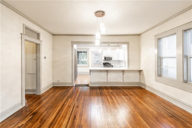 kitchen with kitchen peninsula, stainless steel appliances, white cabinets, dark hardwood / wood-style floors, and hanging light fixtures