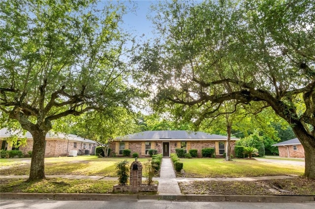 ranch-style house with a front yard and brick siding