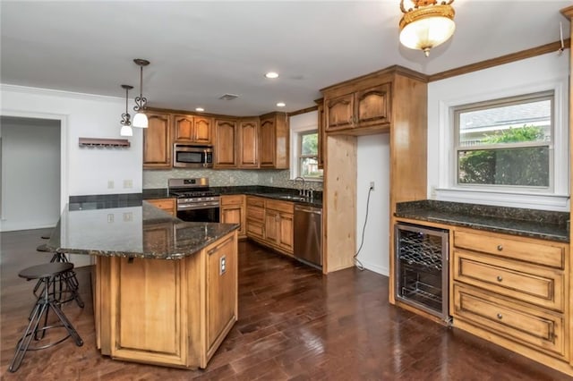 kitchen featuring stainless steel appliances, beverage cooler, brown cabinetry, a sink, and ornamental molding