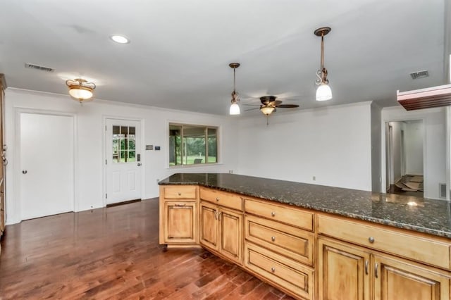 kitchen with crown molding, dark wood-type flooring, ceiling fan, hanging light fixtures, and dark stone countertops
