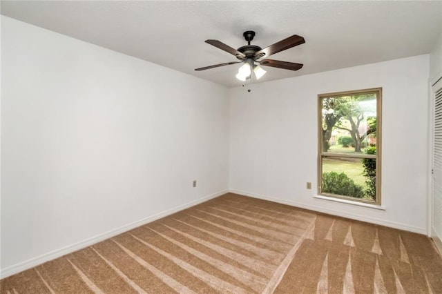 carpeted empty room featuring ceiling fan and baseboards