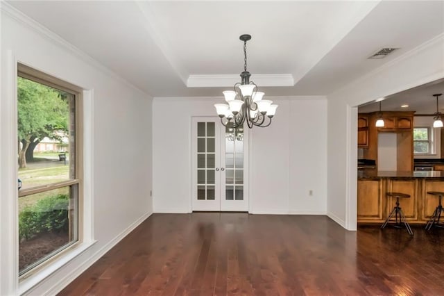 unfurnished dining area featuring a chandelier, dark wood-type flooring, french doors, ornamental molding, and a raised ceiling