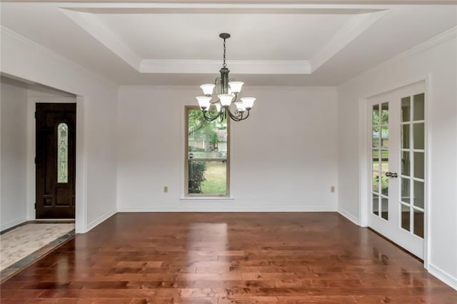 unfurnished dining area featuring wood finished floors, a tray ceiling, a chandelier, and crown molding