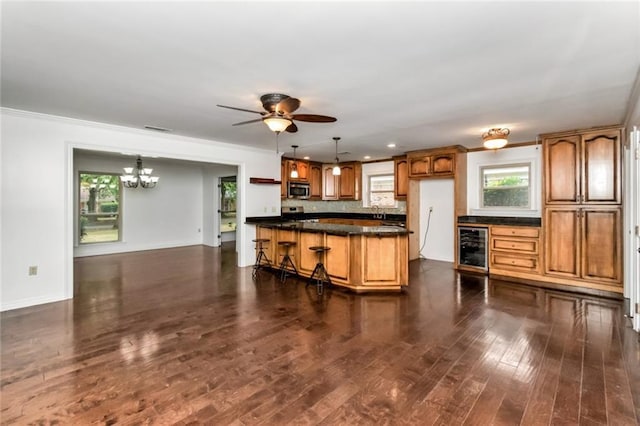 kitchen with stainless steel microwave, dark countertops, beverage cooler, a chandelier, and tasteful backsplash