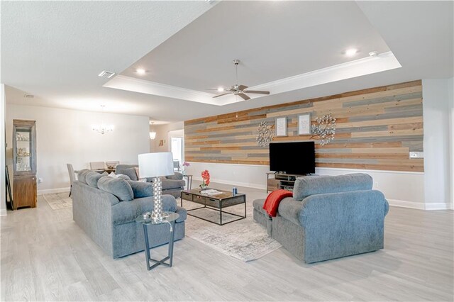 living area with an accent wall, baseboards, wood finished floors, and a raised ceiling