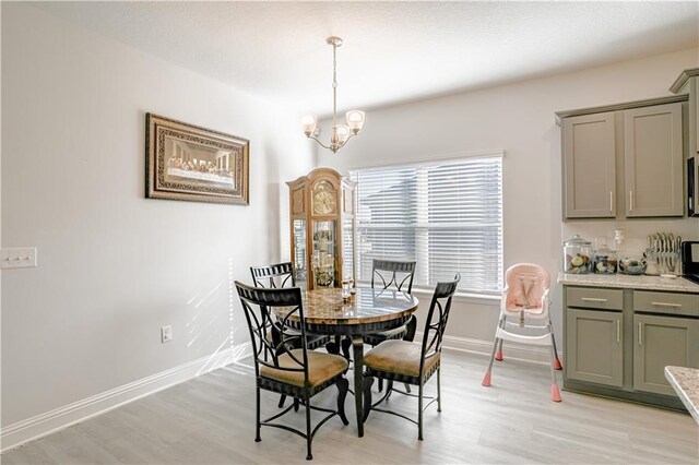 dining area featuring baseboards, light wood finished floors, and a chandelier