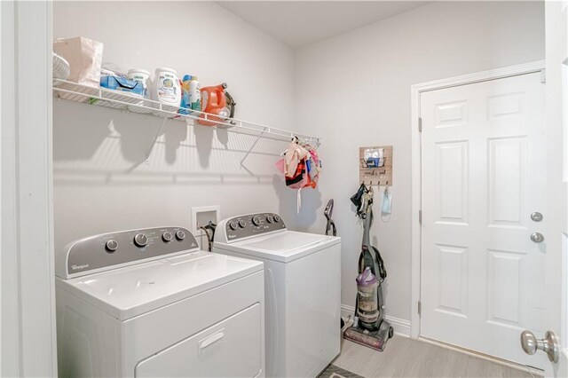 laundry area with laundry area, light wood finished floors, independent washer and dryer, and baseboards