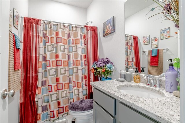 bathroom featuring toilet, a shower with shower curtain, and vanity