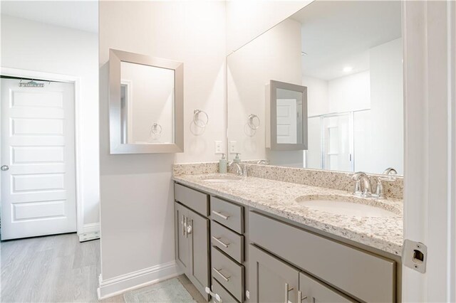 bathroom featuring double vanity, a sink, baseboards, and wood finished floors
