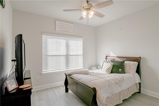 bedroom with a ceiling fan, baseboards, and light wood-style flooring