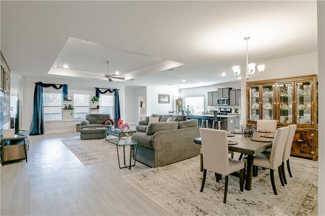 dining room with baseboards, recessed lighting, a tray ceiling, and light wood-style flooring