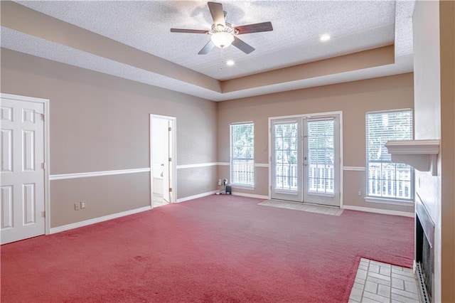 unfurnished room with ceiling fan, french doors, carpet floors, a textured ceiling, and a tray ceiling