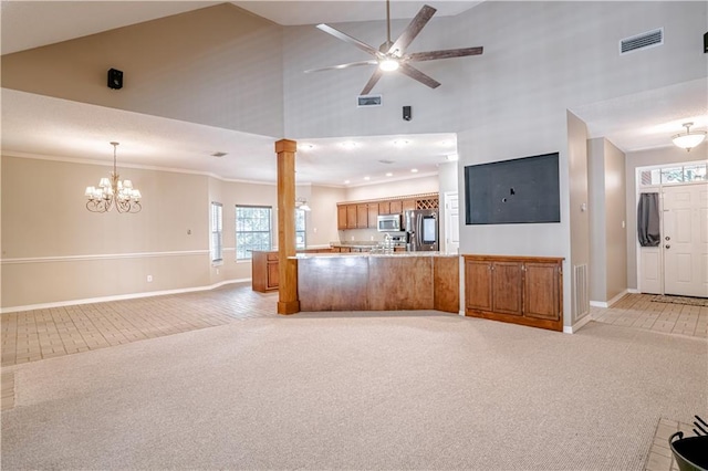 unfurnished living room with high vaulted ceiling, light colored carpet, ceiling fan with notable chandelier, and ornamental molding