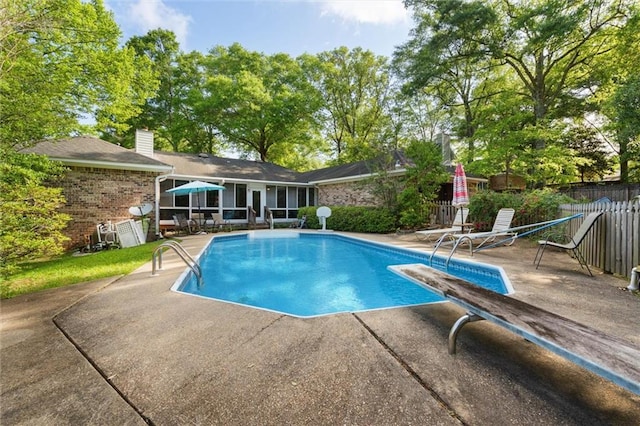 view of swimming pool featuring fence, a fenced in pool, a patio, and a diving board