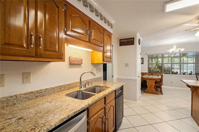 kitchen featuring brown cabinetry, a textured ceiling, a sink, light stone counters, and light tile patterned floors
