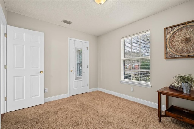 carpeted foyer entrance with a textured ceiling, visible vents, and baseboards