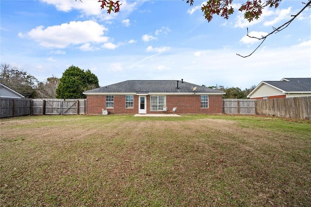 back of house with brick siding, a lawn, and a fenced backyard