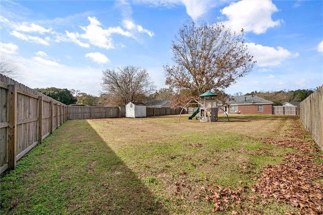 view of yard with a shed, an outbuilding, a playground, and a fenced backyard