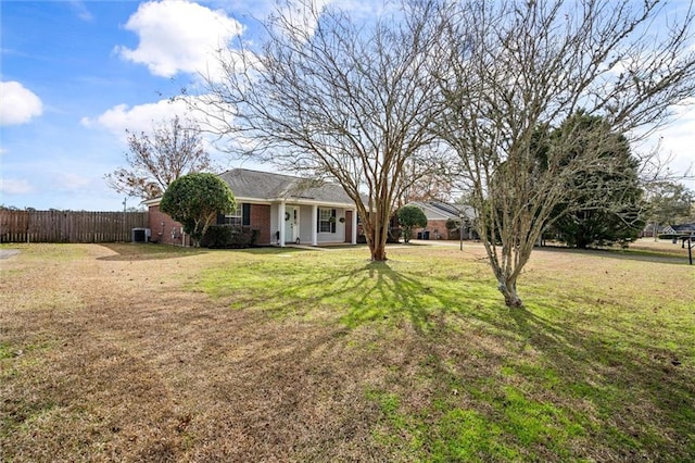 ranch-style home featuring a front lawn, central AC unit, fence, and brick siding