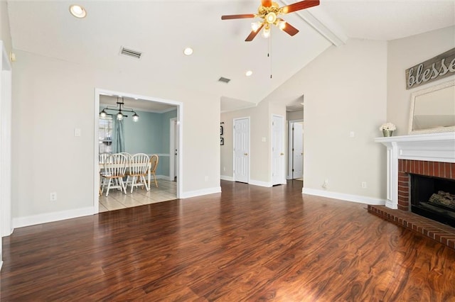 unfurnished living room featuring baseboards, visible vents, wood finished floors, a fireplace, and beam ceiling