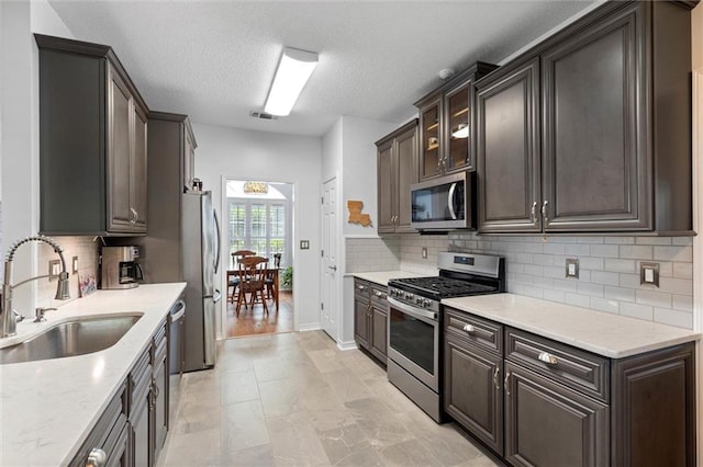 7471 Oak Dr, Foley, AL 36535 - kitchen with stainless steel appliances, decorative backsplash, dark brown cabinetry, and a textured ceiling
