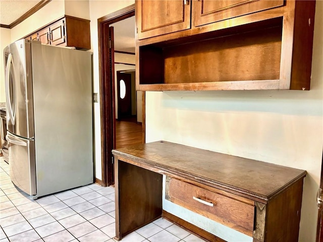 kitchen featuring freestanding refrigerator, light tile patterned flooring, dark countertops, and ornamental molding
