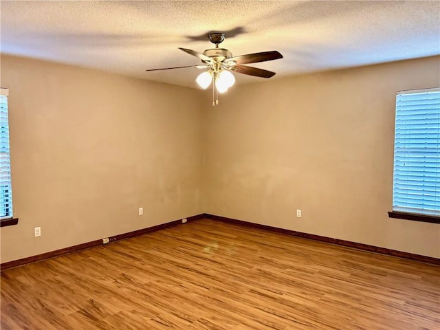 spare room featuring baseboards, a textured ceiling, light wood-style flooring, and ceiling fan