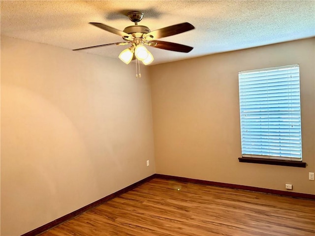 spare room featuring baseboards, a ceiling fan, a textured ceiling, and wood finished floors