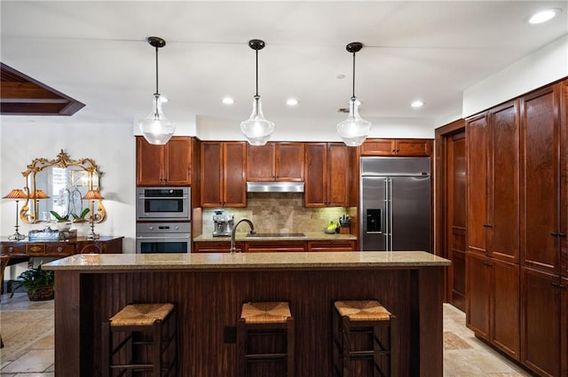 kitchen featuring backsplash, stainless steel built in fridge, a kitchen bar, and a kitchen island with sink