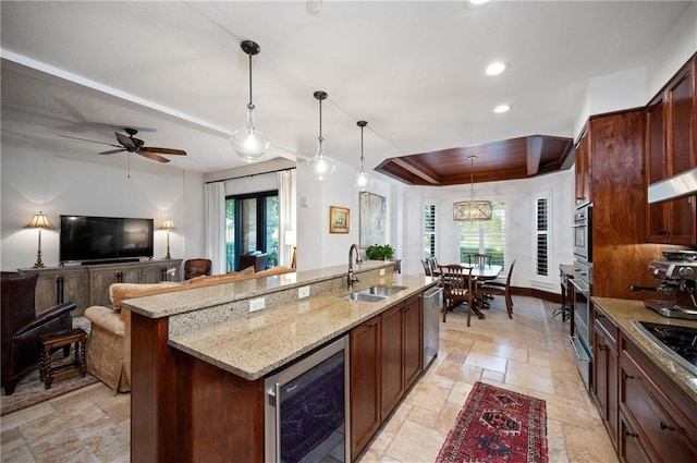 kitchen featuring sink, stainless steel appliances, hanging light fixtures, wine cooler, and a kitchen island with sink