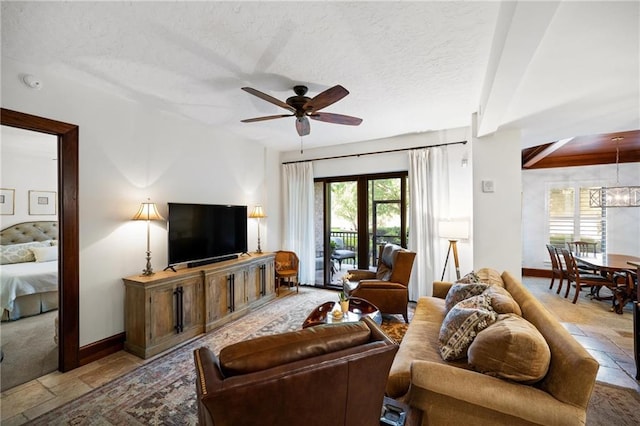 living room featuring beam ceiling, a textured ceiling, a healthy amount of sunlight, and ceiling fan with notable chandelier