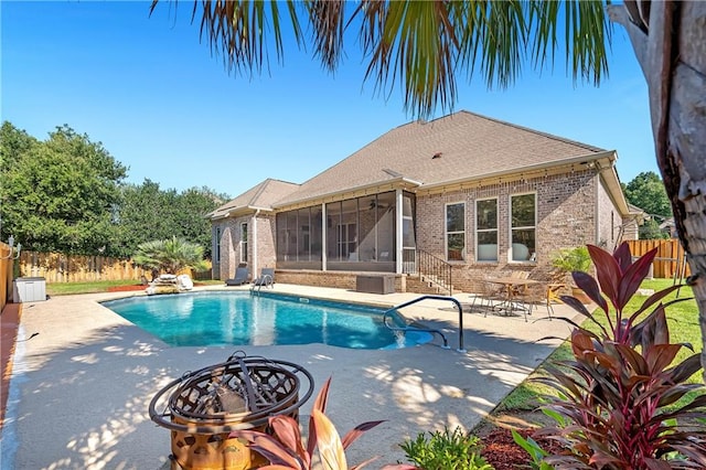 view of swimming pool with central AC unit, a sunroom, a patio area, and an outdoor fire pit