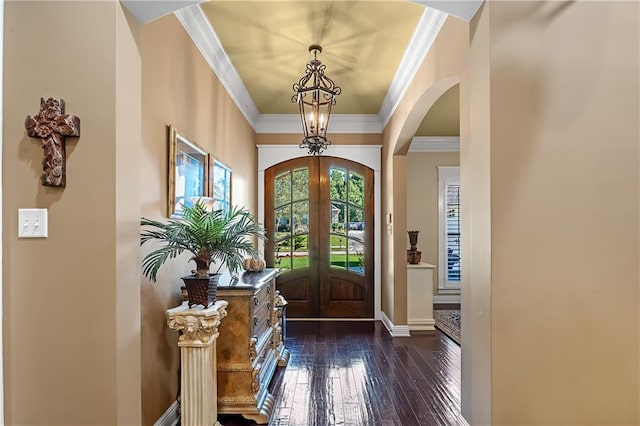 foyer entrance with french doors, a notable chandelier, crown molding, and dark hardwood / wood-style flooring