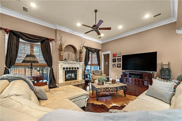 living room with hardwood / wood-style flooring, crown molding, ceiling fan, and a fireplace