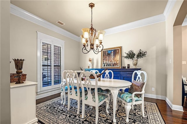 dining room featuring crown molding, dark hardwood / wood-style flooring, and a chandelier