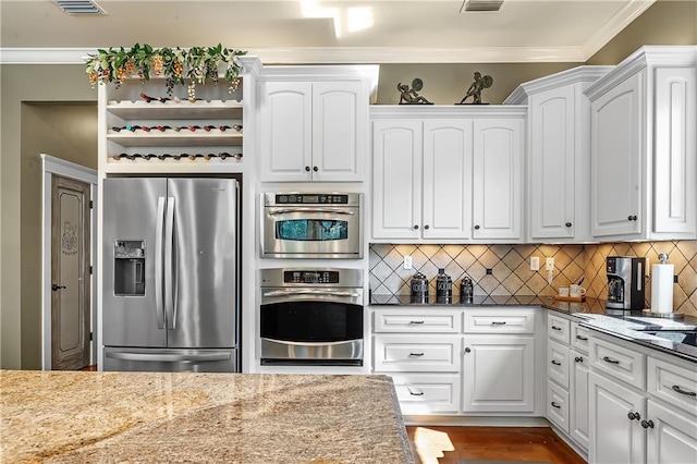 kitchen featuring white cabinets, appliances with stainless steel finishes, ornamental molding, and light stone countertops