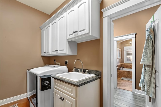 washroom featuring sink, light hardwood / wood-style flooring, washer / clothes dryer, and cabinets