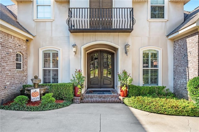 view of exterior entry featuring french doors and a balcony