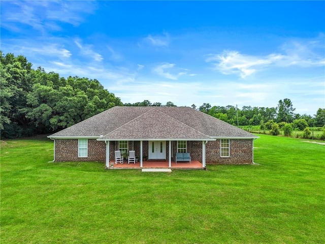 ranch-style home with brick siding, a patio, a front lawn, and roof with shingles