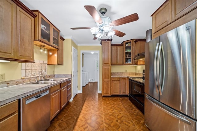 kitchen featuring brown cabinets, stainless steel appliances, glass insert cabinets, a sink, and under cabinet range hood