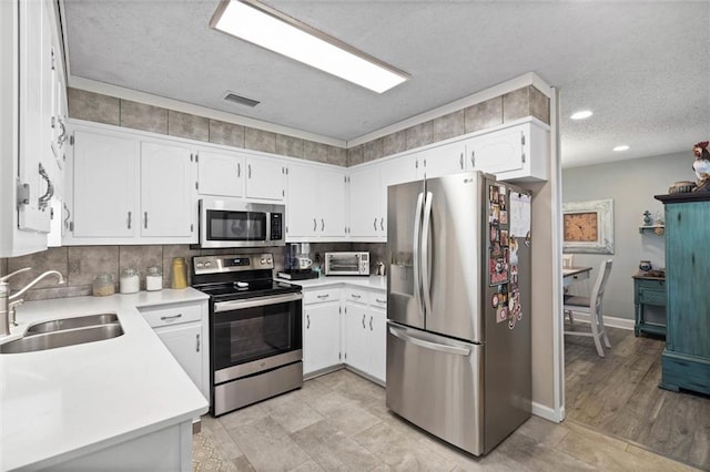 5719 Laurel Dr, Satsuma, AL 36572 - kitchen with appliances with stainless steel finishes, a sink, a textured ceiling, tasteful backsplash, and light countertops